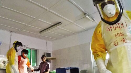 medical personnel with full body suit on treating patient 