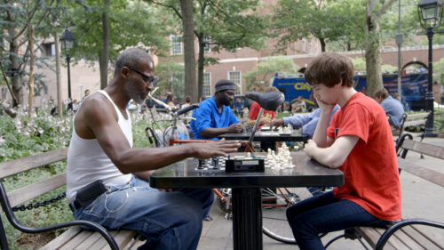 man and boy playing chess at a park