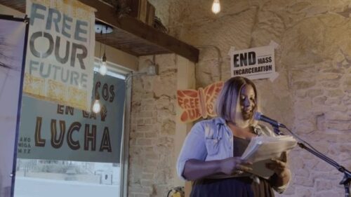 woman speaking into mic with signs behind her that read 