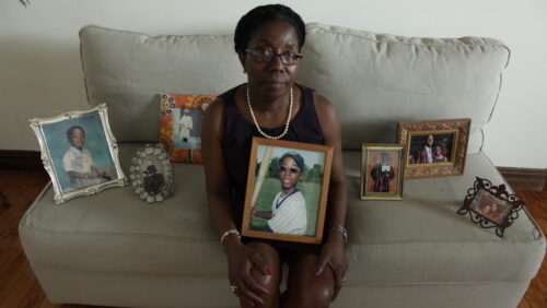 Woman sitting on couch holding a picture of a young boy
