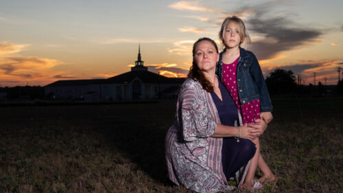 Mom with her child in a field next to a church
