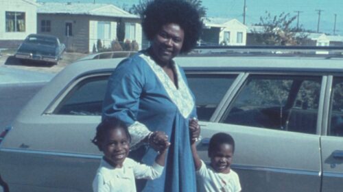 woman and child standing outside blue car