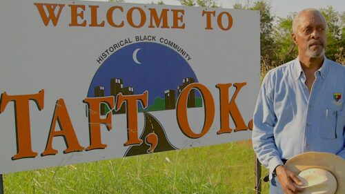 man standing next to welcome to Taft, OK sign