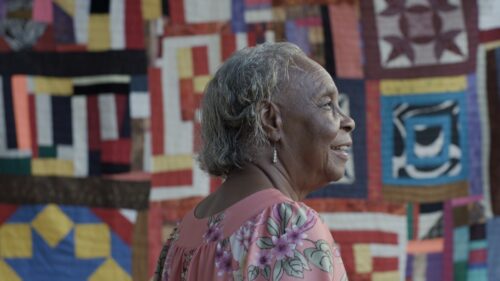 woman standing in front of quilt