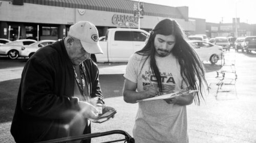Young and older man registering to vote outside grocery store
