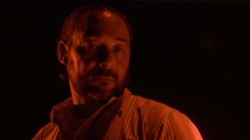 Man in red lighting staring down