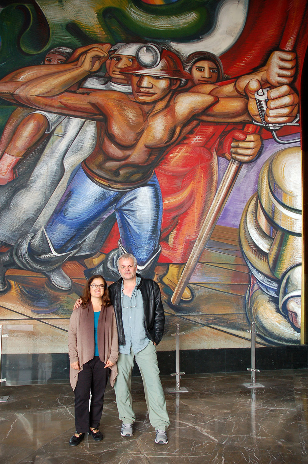 Director Lorena Manriquez with co-director Miguel Picker under a Siqueiros painting.