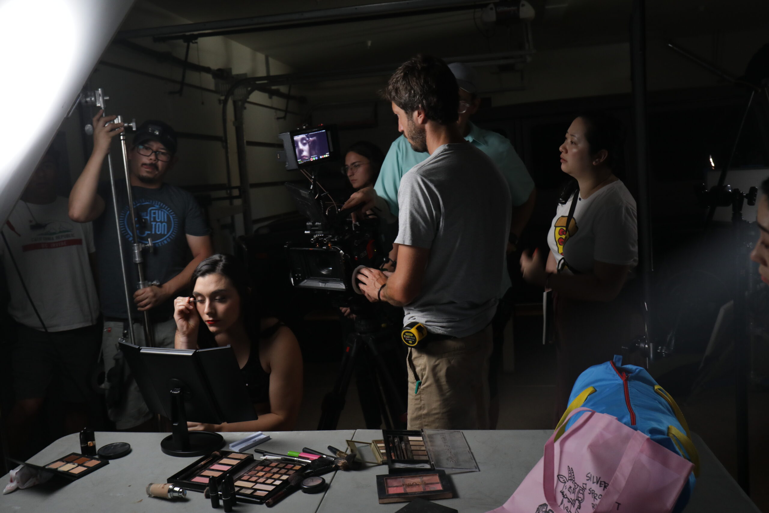 Yu Gu, at right, setting up a shot for A Woman's Work, with cheerleader putting on makeup and film crew all around them