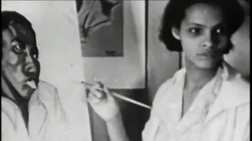 Black woman with paintbrush in hand in front on painting of a black person in black and white