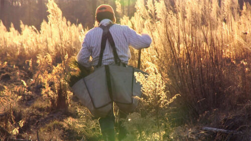 Man walking in nature with large bags