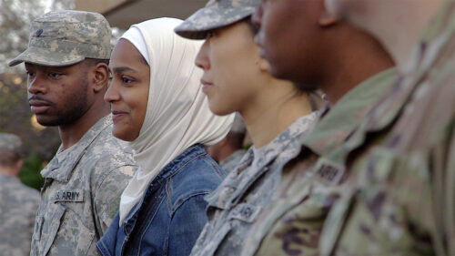 woman wearing hijab standing in line with people in military uniform