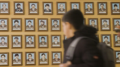 boy walking past wall of photos