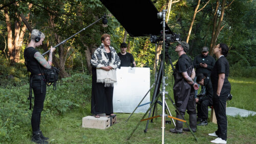Woman standing outside with camera crew around her