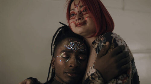 person wearing stick on jewles on face being embraced by someone else with face painting