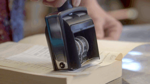 someone stamping a book with a return date