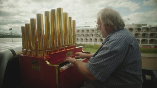 man playing piano like organ in the back of a flatbed truck