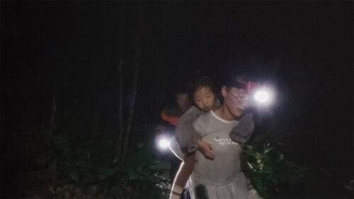 Child on mans back with headlamps on in a dark place