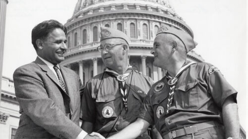 three men two in military uniforms shaking hands
