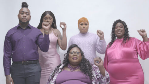 diverse group of people standing with their fists raised looking at the camera in front of a white background