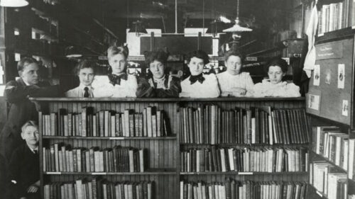 old photo of a group of women standing behind bookshelf