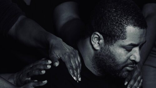 Man with head down and hands on his shoulders. A somber mood