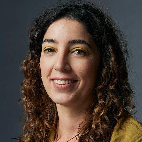 Headshot of woman with curly brown hair and light tan skintone