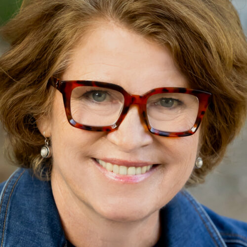 Smiling woman wearing tortoiseshell-patterned glasses.