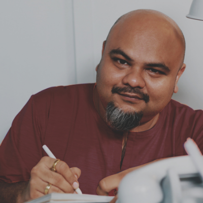 headshot of man with bald head and facial hair with rings on