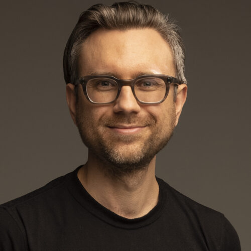White man with glasses in a black t-shirt