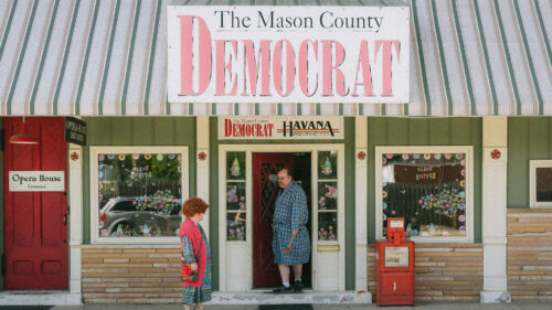 Two people stand outside the storefront of 